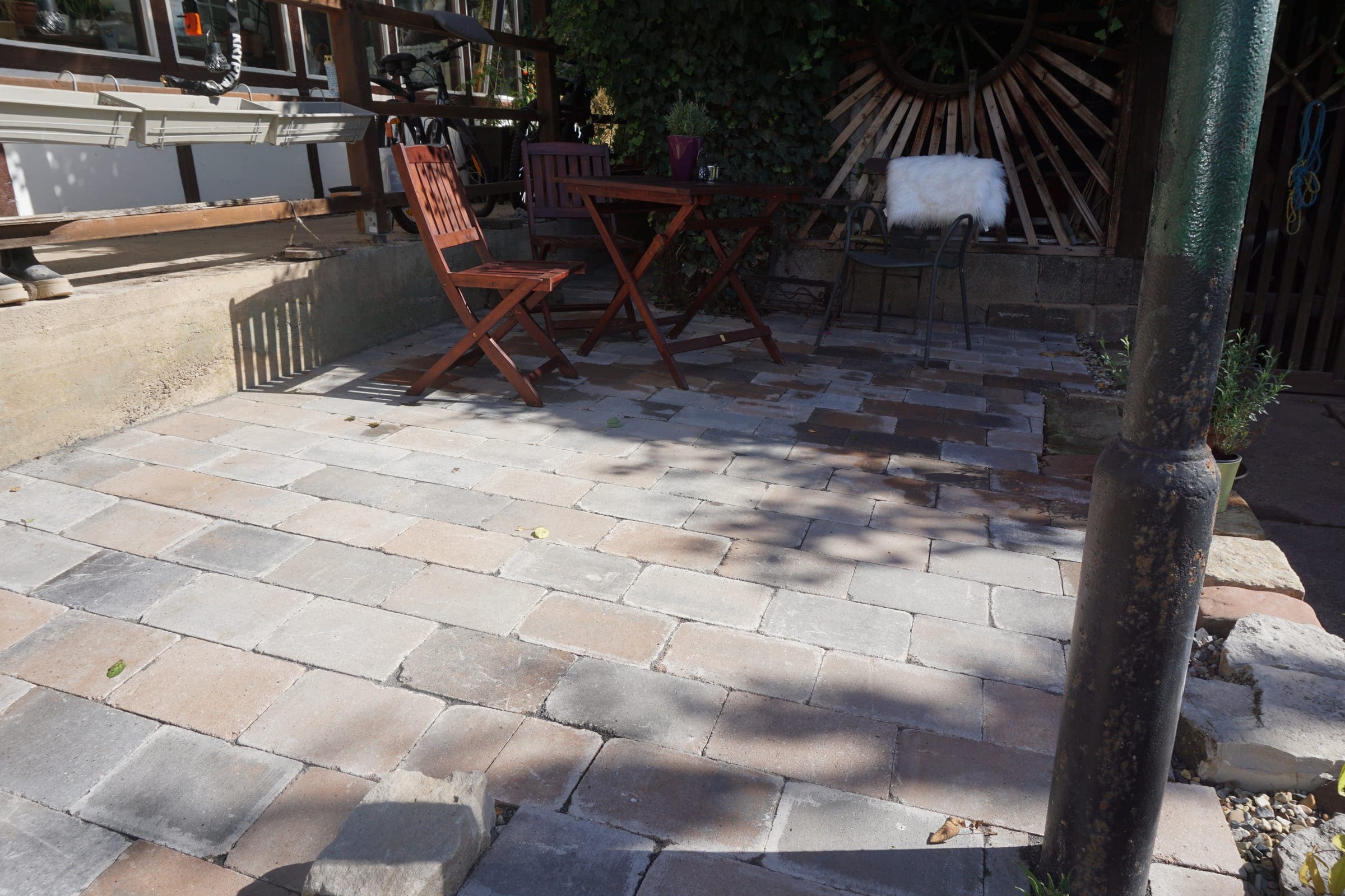 Pflasterterrasse aus Sandstein mit Sitzmöbeln vor einem Fachwerkhaus