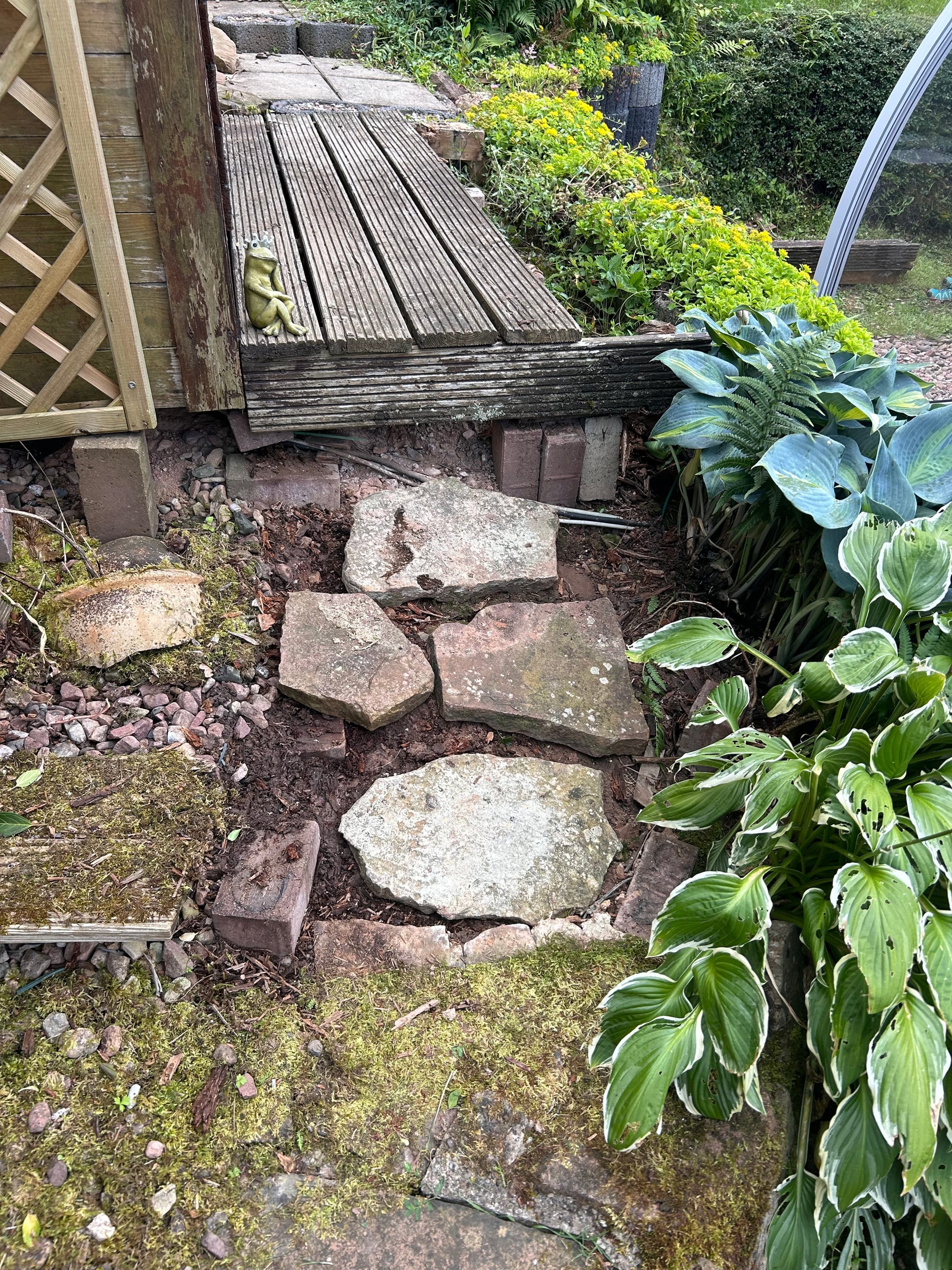 Alte, verwitterte Holzterrasse mit unregelmäßigen Natursteinplatten