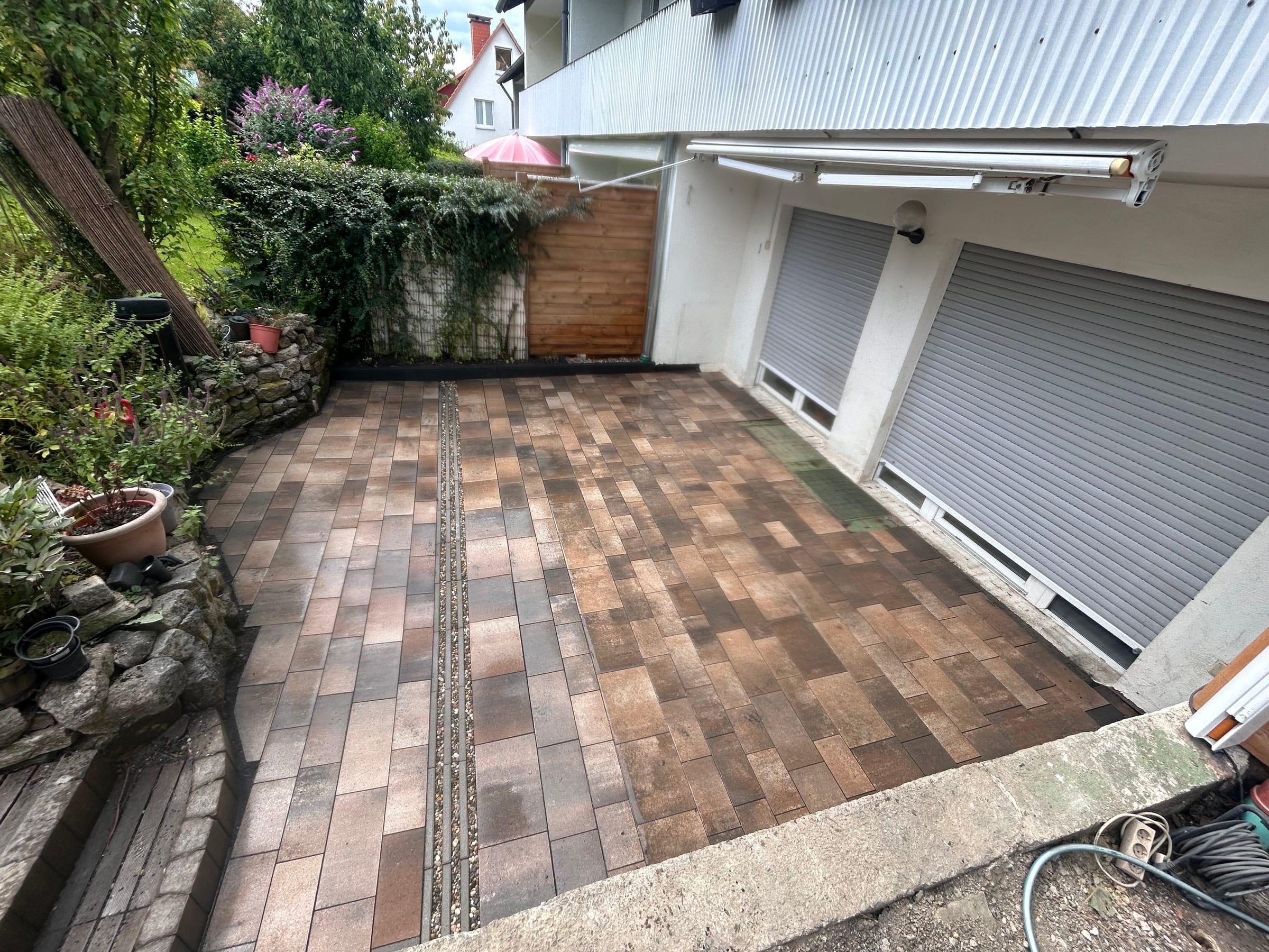Fertige WPC-Terrasse in warmen Brauntönen vor weißer Garagenfront