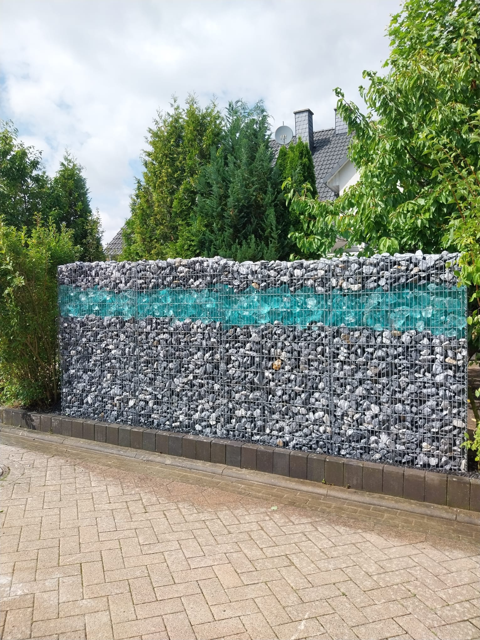 Gabionenwand als Sichtschutz an gepflasterter Fläche